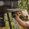 Person is adjusting the angle on the 10W Universal Solar Power Pack that is mounted on a Moultrie Feeder.