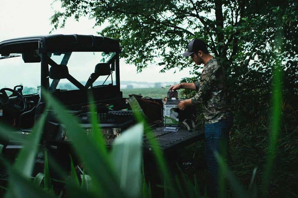 Man pulling out a Delta Cellular Trail Camera from box in back of ATV