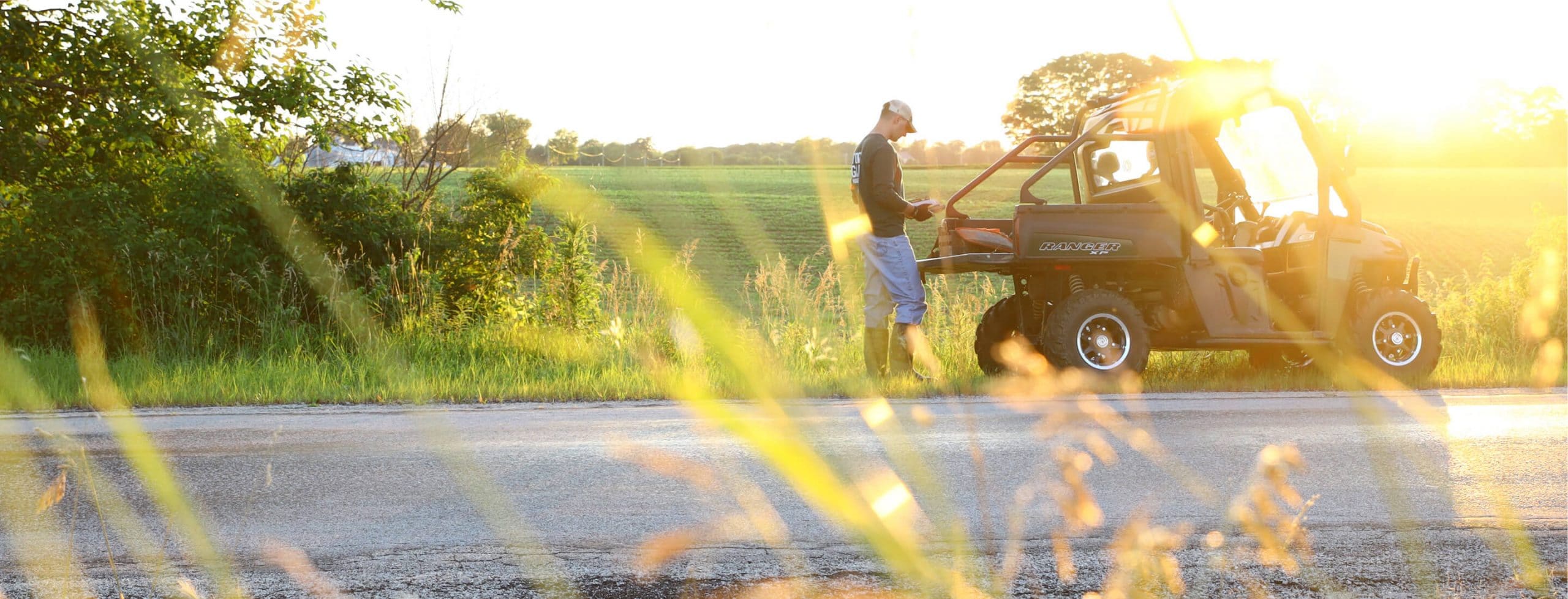 Man standing behind ATV on side of the road