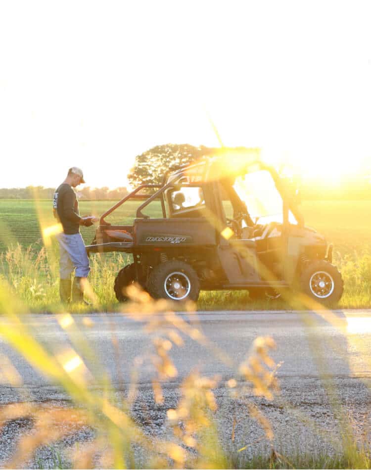 Man standing behind ATV on side of the road