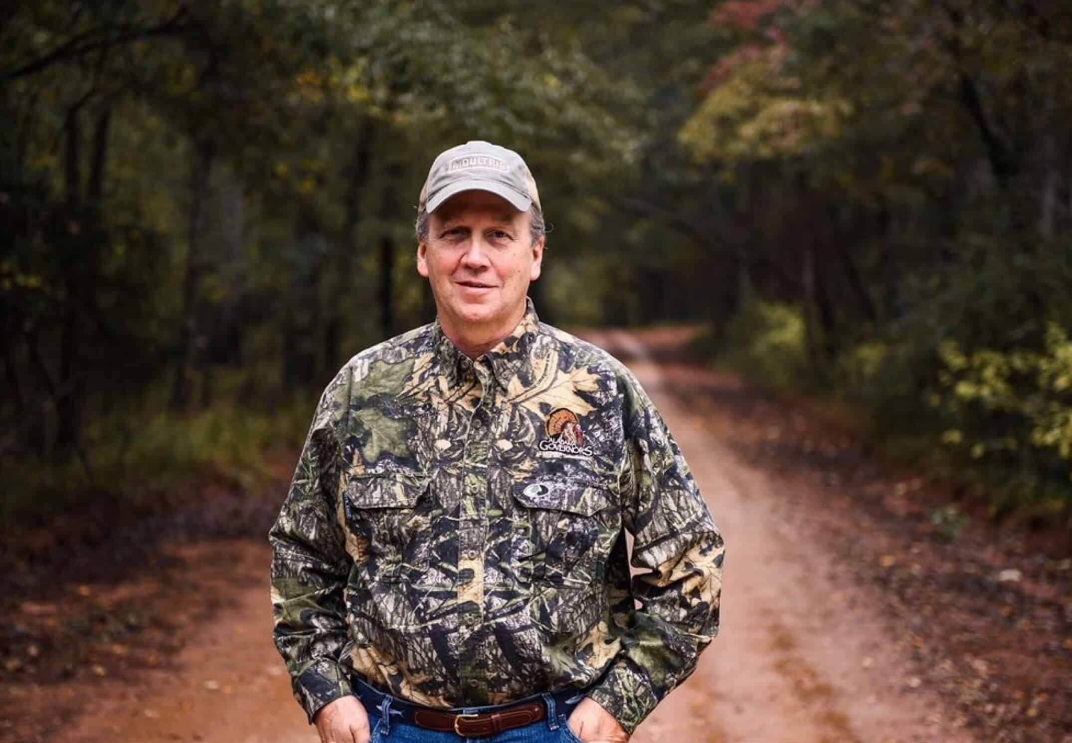 Man in camo standing on trail in the woods