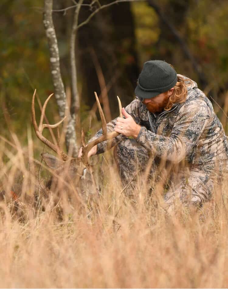 Man dressed in camo tagging deer antlers