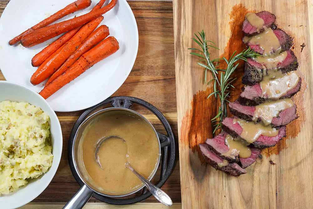 Table top view of cooked Venison Roast with Carrots, potatoes, and gravy.